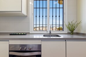 A kitchen with a window, a sink, and a stove. - Charming Apartment for 4 Near Golf & Sea (Rincón de la Victoria)