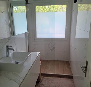 Un bagno con lavandino, specchio e doccia.