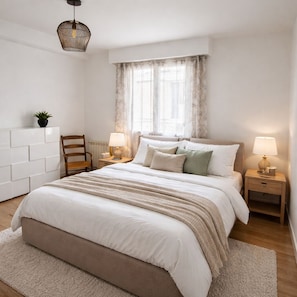 Ein Schlafzimmer mit einem großen Bett, zwei Nachttischen mit Lampen, einem Sessel, einem Heizkörper und einer Hängeleuchte.