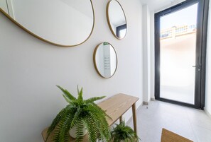 A room with three wall-mounted mirrors, a wooden bench, and a potted fern. - Brand New · Modern Comfort in Málaga by VGC (Málaga)