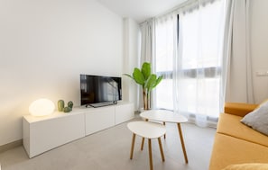 A modern living room with a flat-screen TV, a white console, a plant, a small table, and a sofa. - Brand New · Modern Comfort in Málaga by VGC (Málaga)