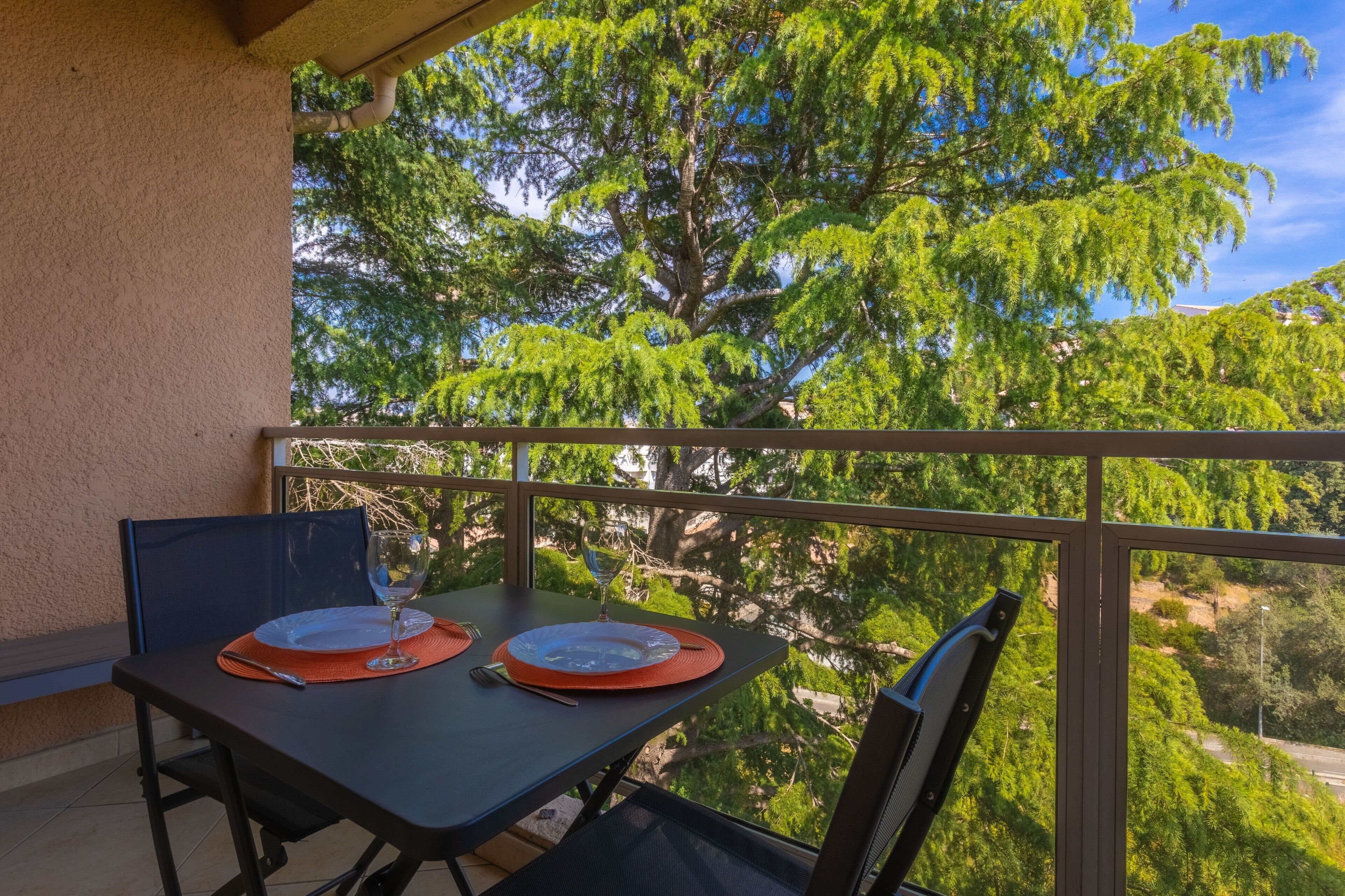 Un balcón con una mesa dispuesta para dos personas, con vistas a un paisaje verde exuberante.