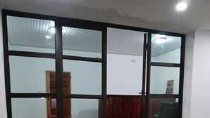 Een kamer met een grote schuifglazen deur, een houten vloer met een patroon en een voetmat.