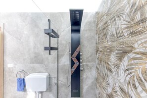 Une salle de bain équipée d’une douche moderne, de toilettes et d’un porte-serviettes.
