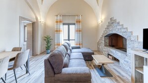 Una sala de estar moderna con chimenea de piedra, un sofá, una mesa de comedor y un televisor.