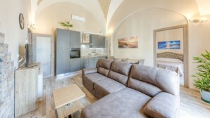 Una sala de estar moderna con un sofá, televisor, cocina y comedor.