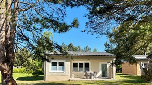 Ein bungalow mit Terrasse, überdachter Veranda und Garage.