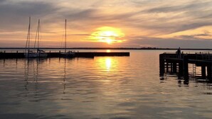 Ein Sonnenuntergang über ruhigem Wasser mit Booten an einem Steg.