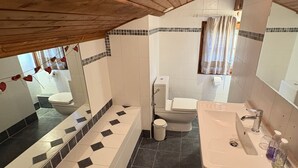 A bathroom with a wooden ceiling, a bathtub, a toilet, and a sink.