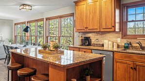 A kitchen with wooden cabinets, a granite countertop, and a large window. - Sleeps 20! 2 Lakefront Homes w/ Hot Tub, Firepit, Game Room, Community Amenities (Long Pond)