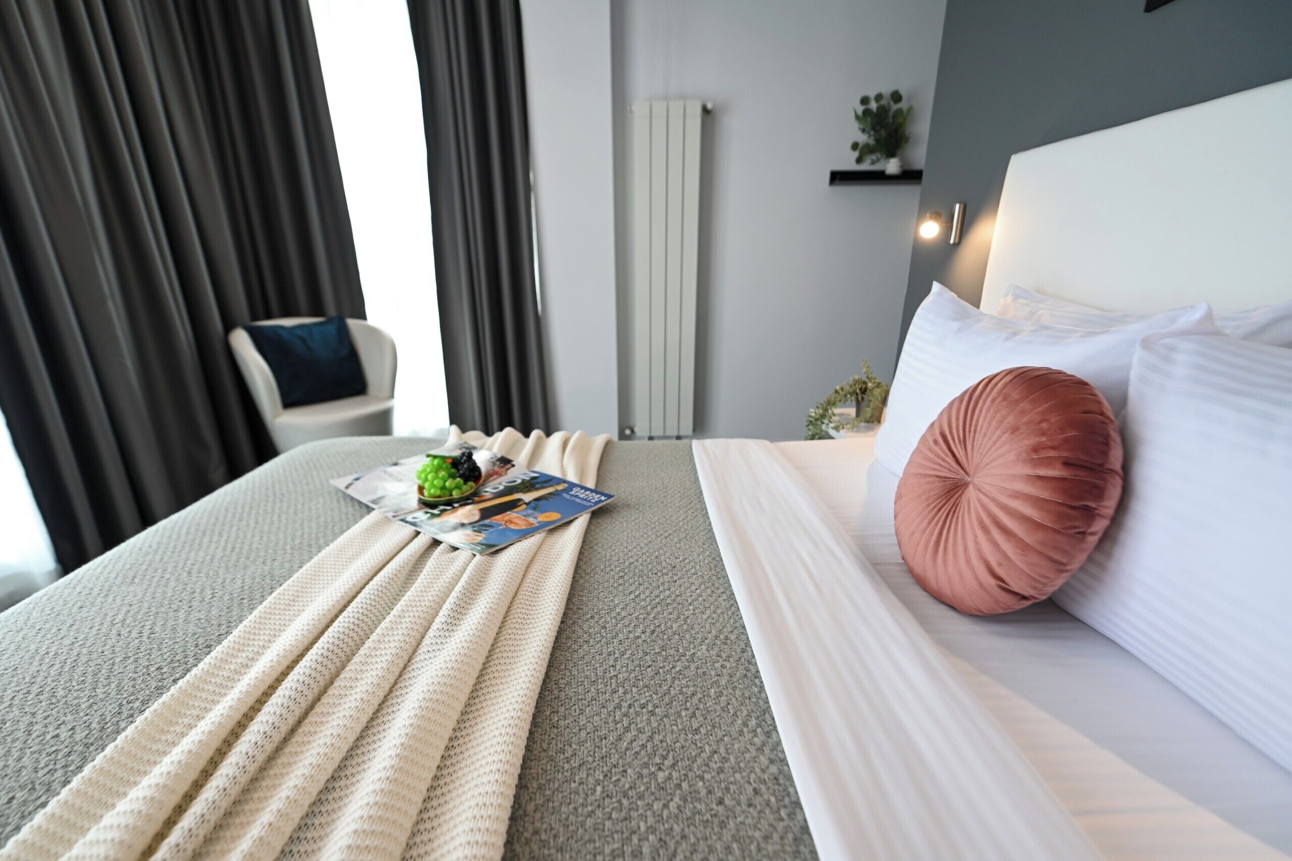 A neatly made bed with pillows, a blanket, and a magazine on the bed.