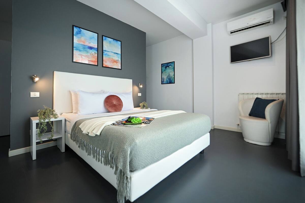 Un dormitorio moderno con cama, mesitas de noche, televisor y obras de arte en las paredes.