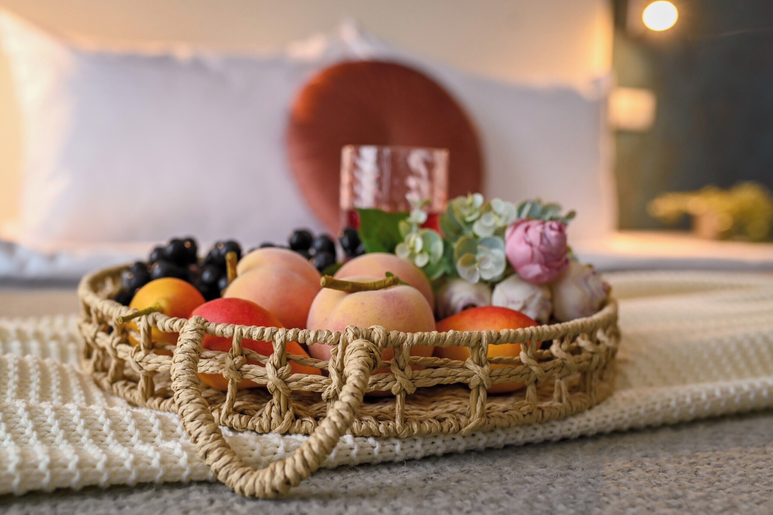 Un panier tressé contenant des fruits et un objet décoratif, le tout posé sur une surface texturée.