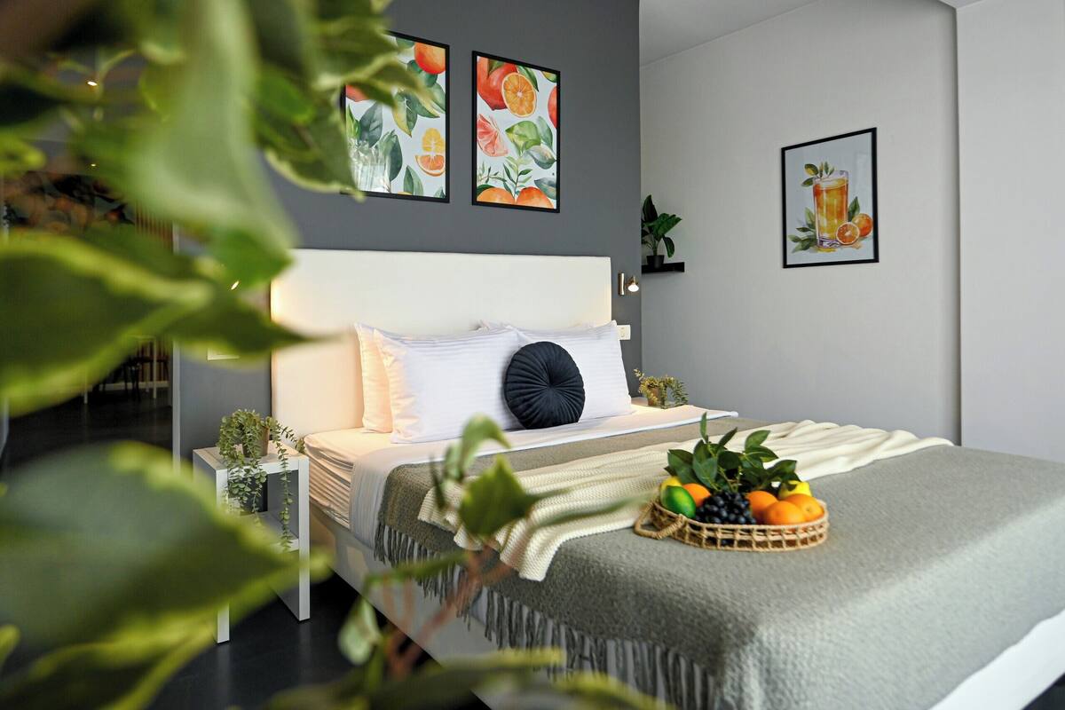 Un dormitorio moderno con cama, plantas en las mesitas de noche y obras de arte en las paredes.