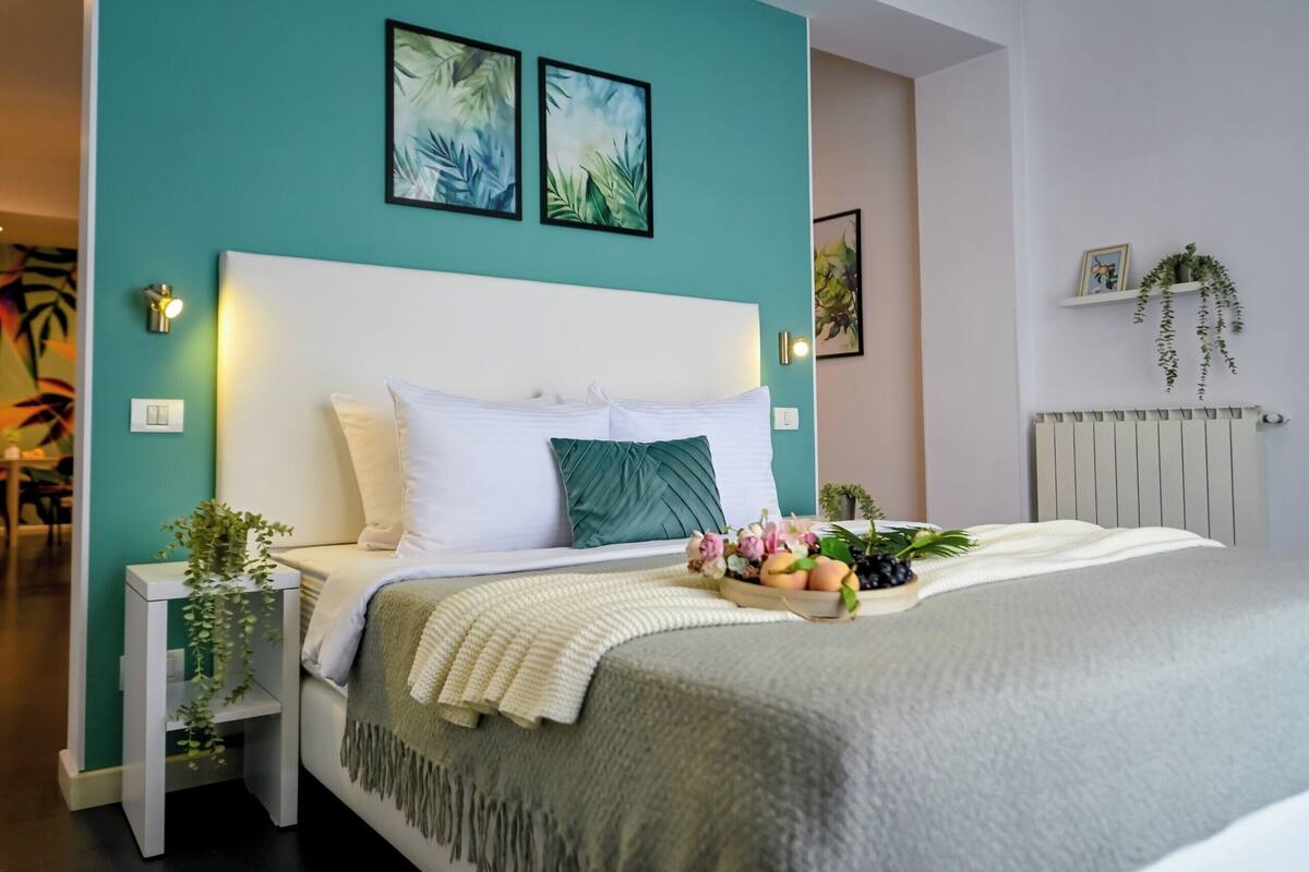 Un dormitorio ordenado con cama, mesitas de noche y cuadros en la pared.