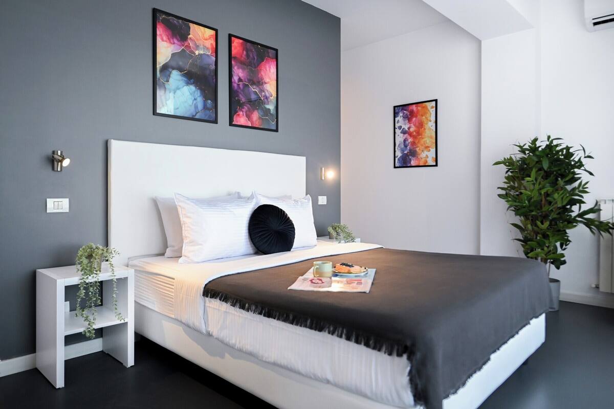 Un dormitorio moderno con una cama grande, cabecera blanca y arte abstracto en las paredes.