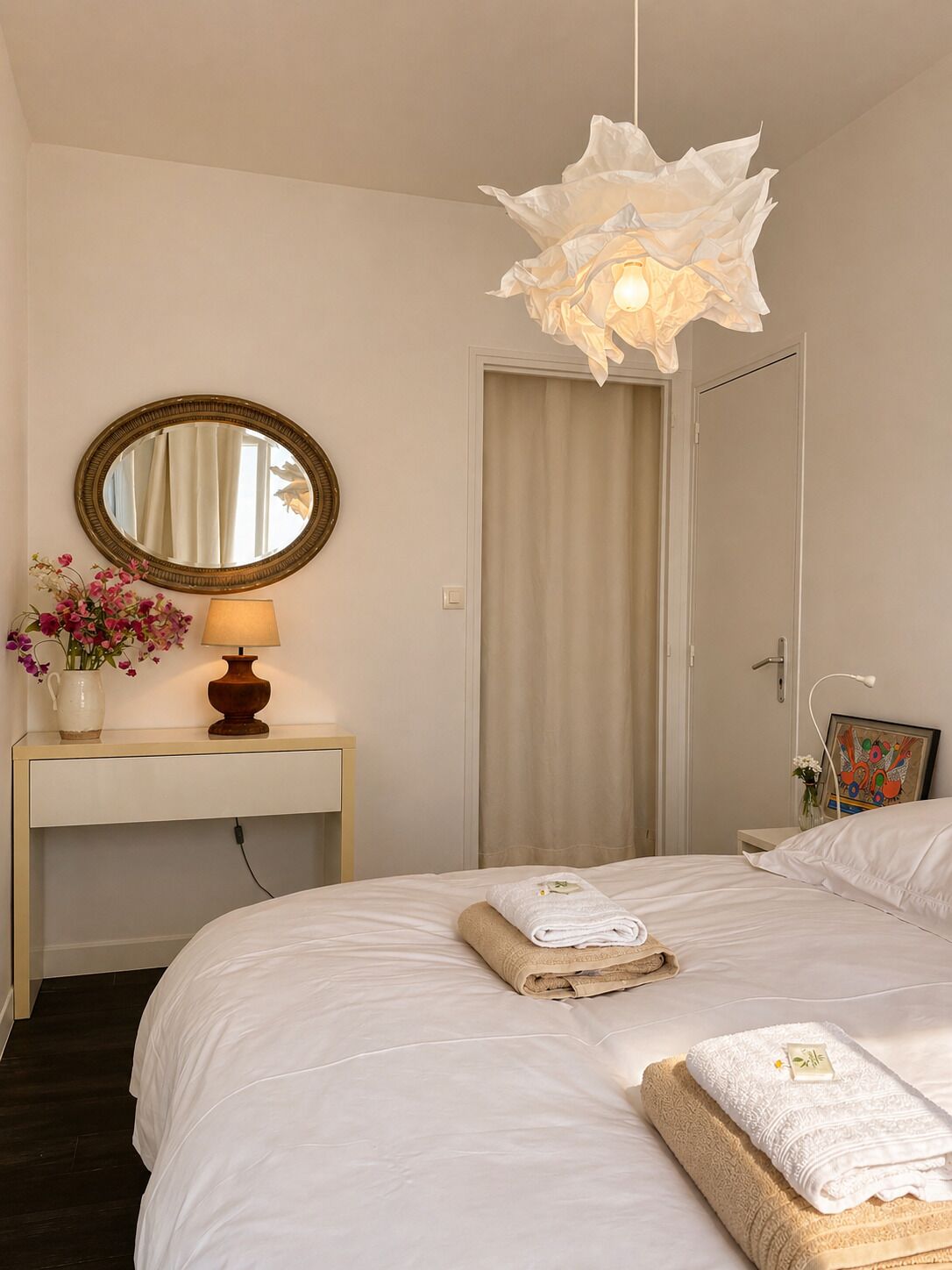 Une chambre à coucher avec un lit, une table de chevet avec une lampe, un miroir et une porte.