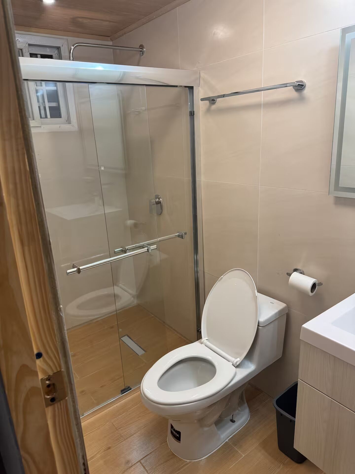 A bathroom with a glass-enclosed shower, a toilet, and a sink.