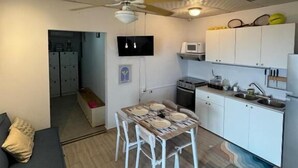 Un espacio habitable compacto con kitchenette, comedor y ventilador de techo.