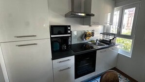 A modern kitchen with white cabinets, a microwave, a toaster, a coffee maker, and a sink. - Captain YOO - A Stopover in Fécamp: Terrace with Ocean View (Fécamp)