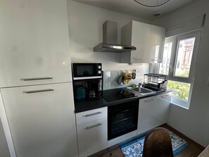Eine moderne Küche mit weißen Schränken, einer Mikrowelle, einem Toaster, einer Kaffeemaschine und einem Spülbecken.