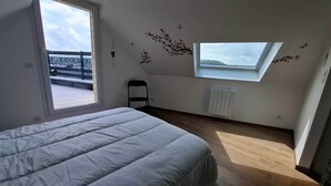 A bedroom with a bed, a window, a radiator, and a chair. - Captain YOO - A Stopover in Fécamp: Terrace with Ocean View (Fécamp)
