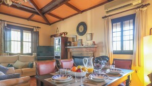 A dining area with a wooden table set for breakfast, a sofa, and a fireplace. - Holiday Home Los Miradores, Marchena, Seville (Marchena)