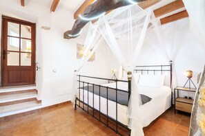 Un dormitorio con una cama, una mesita de noche, una lámpara, una puerta de madera y una escalera.