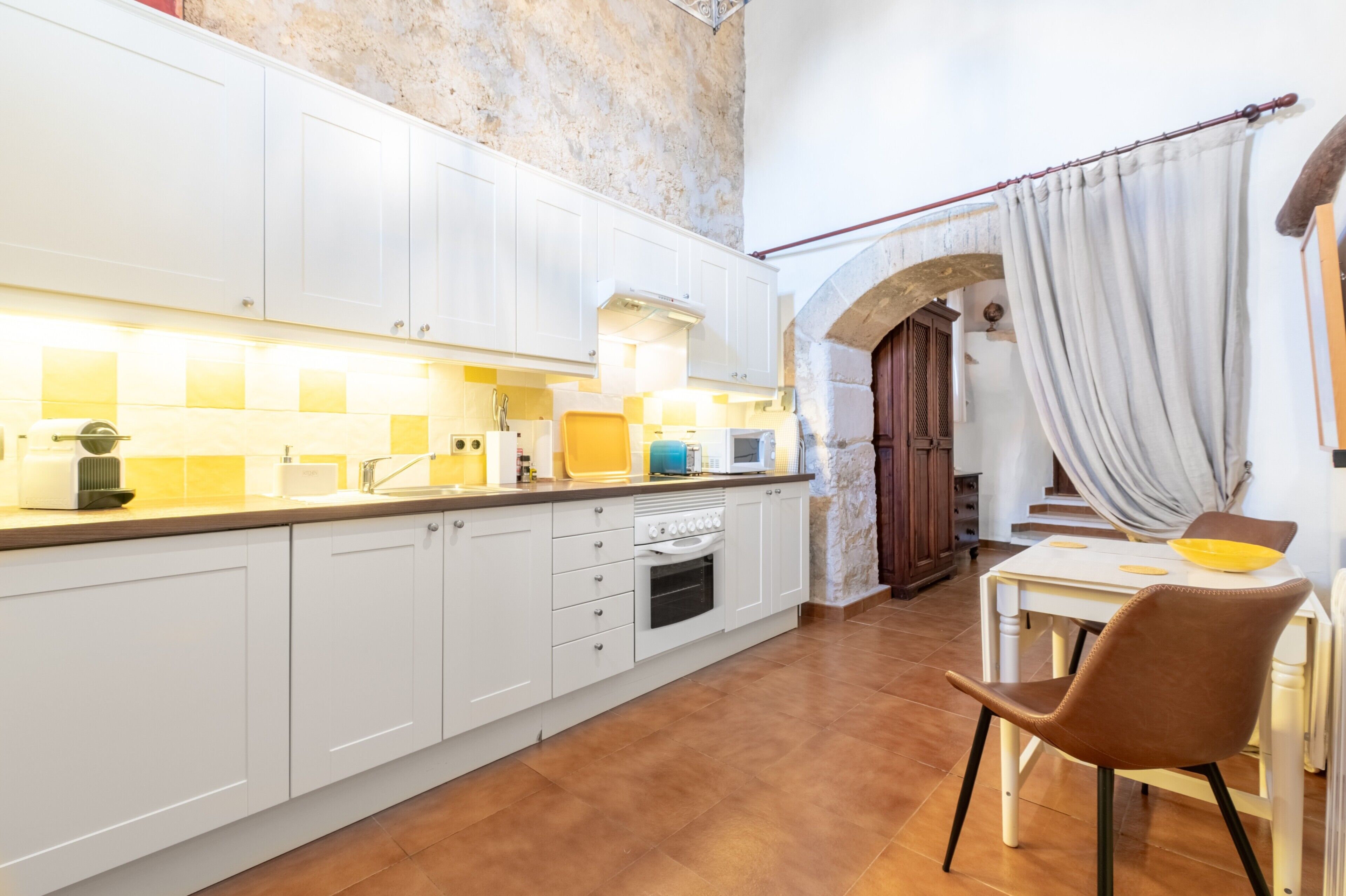 A kitchen with white cabinets, a stove, and a dining area with a table and chairs.