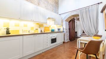 A kitchen with white cabinets, a stove, and a dining area with a table and chairs.