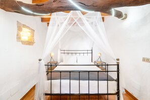 A bed with a metal frame, white bedding, and a canopy. There are two bedside lamps and a wall-mounted light. - Apartment Tierra with Communal Pool, Wi-Fi and Air Conditioning (Porreres)