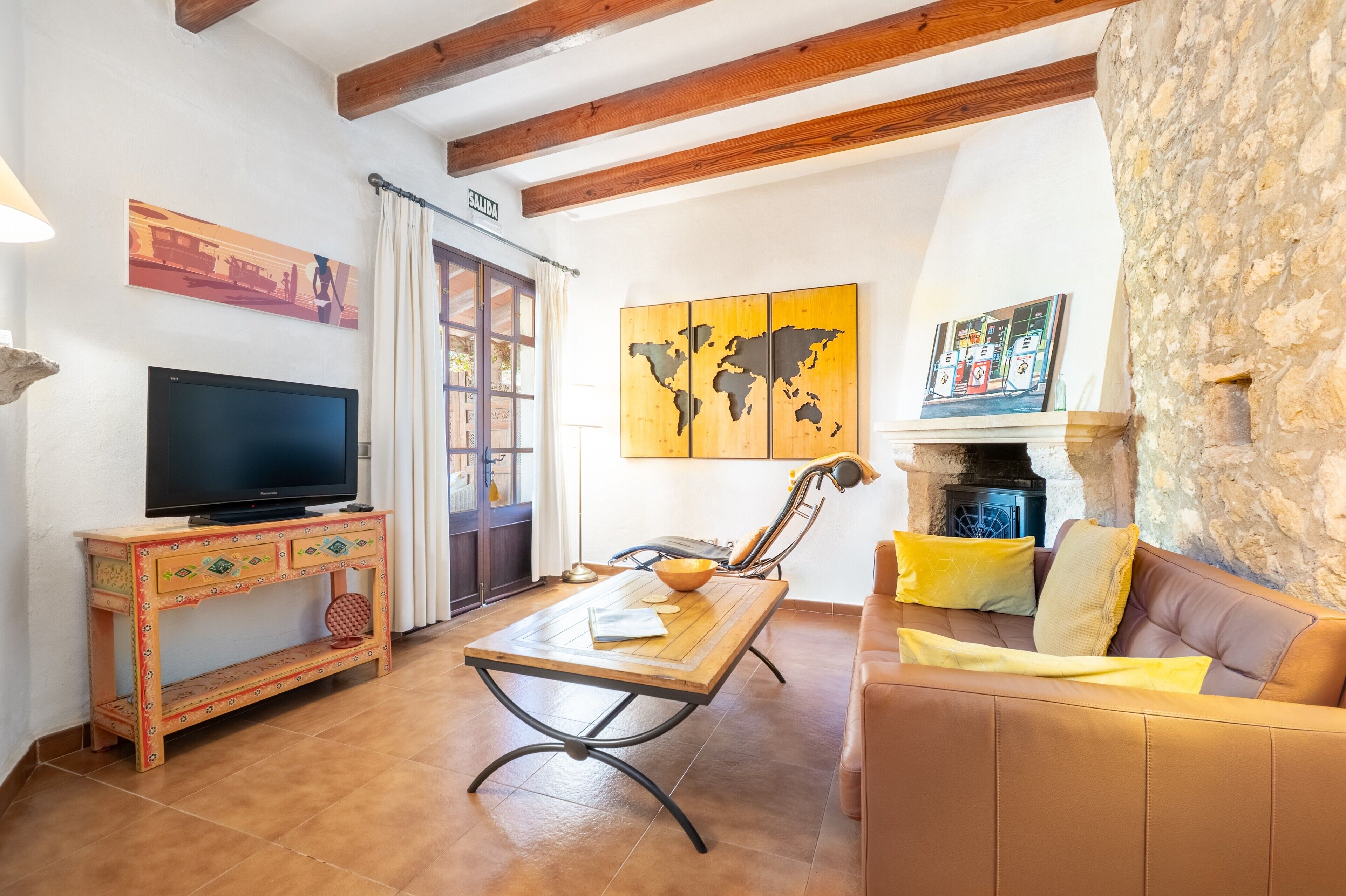 Una sala de estar con televisor, muebles de madera, una pared de piedra y chimenea.