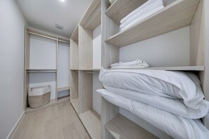 Ein Schlafzimmer mit eingebauten Holzbögen, einem Bett mit weißer Bettwäsche und einem Aufbewahrungskorb.