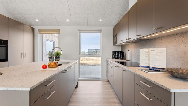 Una cocina moderna con una isla grande, horno empotrado y vistas a través de la ventana.