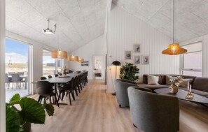 A spacious room with a long dining table, multiple chairs, a sofa, and a large plant. - Cozy home in Bogense with sauna (Bogense)