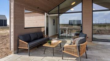 Un espace extérieur aménagé, abrité et doté d’un canapé, de chaises et d’une table.