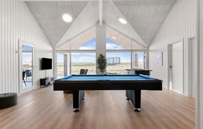 A pool table in a room with large windows, wooden floors, and a flat-screen TV. - Cozy home in Bogense with sauna (Bogense)