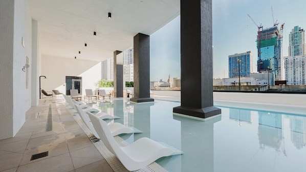 Ein moderner, überdachter Pool mit freiem Blick auf den Stadtpanoramablick und Baukräne.