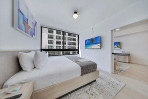 Ein modernes Schlafzimmer mit einem großen Bett, Blick auf ein Gebäude durch ein Fenster und einem Gemälde an der Wand.