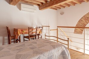 Un dormitorio con una cama, una mesa de madera con sillas, una escalera y una pared de ladrillo.