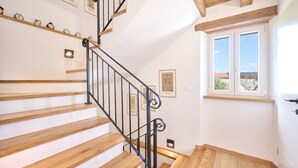 A staircase with wooden steps and black metal railings, a window with a view of the outside, and framed pictures on the wall. - Casa Pove by Villas Guide (Baredine)