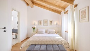 A bedroom with a bed, bedside tables, a bench, a mirror, and framed pictures on the wall. - Casa Pove by Villas Guide (Baredine)