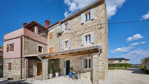 A stone building with a covered porch, a wooden door, and a small outdoor seating area. - Casa Pove by Villas Guide (Baredine)