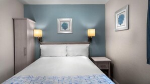 A hotel room with a bed, two bedside lamps, a wardrobe, and two framed pictures on the wall. - Bright 2-bedroom apartment with AC in cool North Myrtle Beach maritime (North Myrtle Beach)