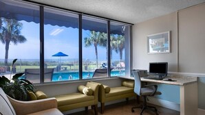 A room with a desk, computer, and a view of a pool and palm trees. - Bright 2-bedroom apartment with AC in cool North Myrtle Beach maritime (North Myrtle Beach)