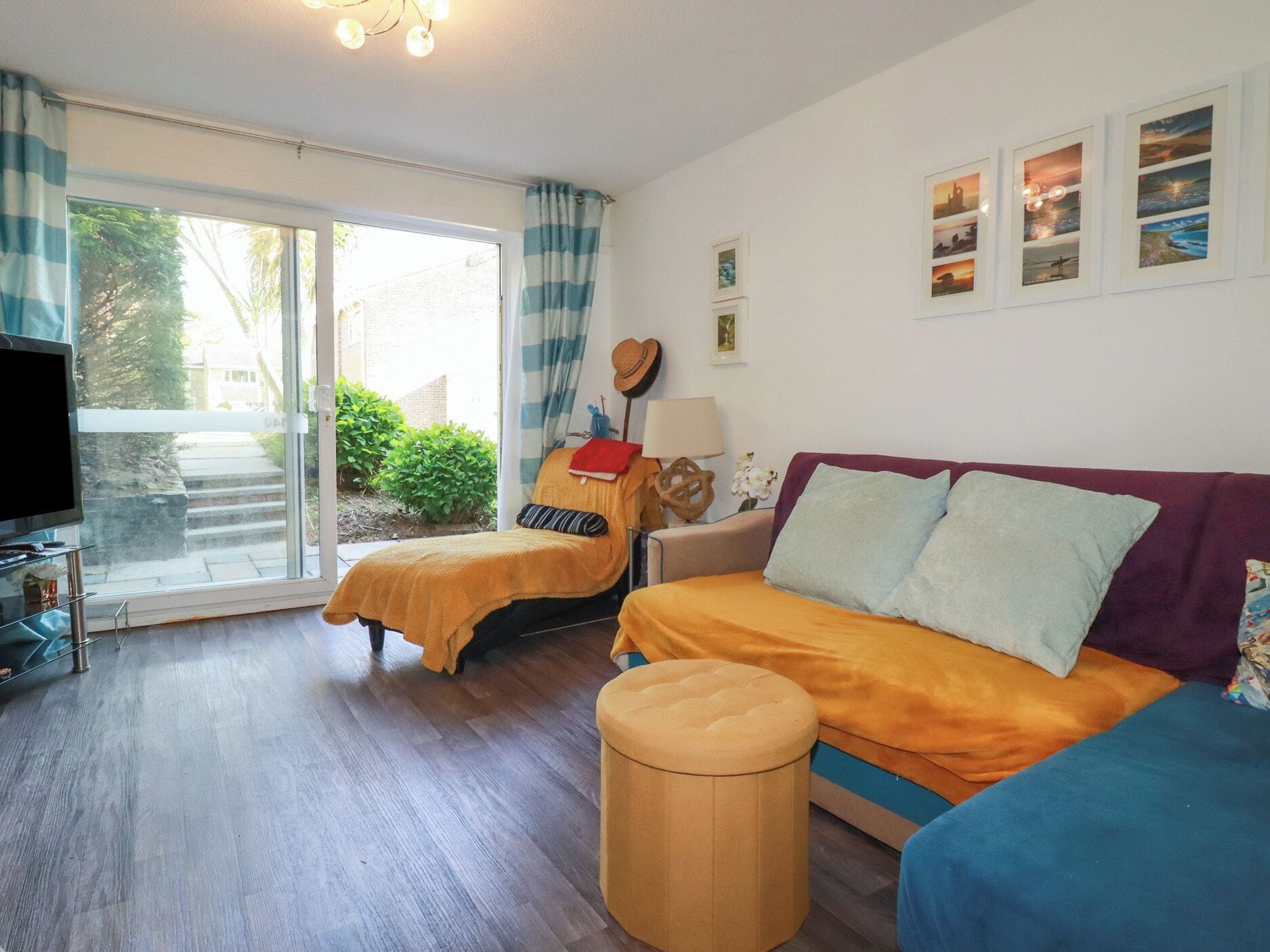Een kamer met een bed, een bank, een televisie en een raam met gordijnen.