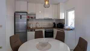Eine moderne Küche mit Kühlschrank, Backofen, Spüle und Esstisch mit Stühlen.