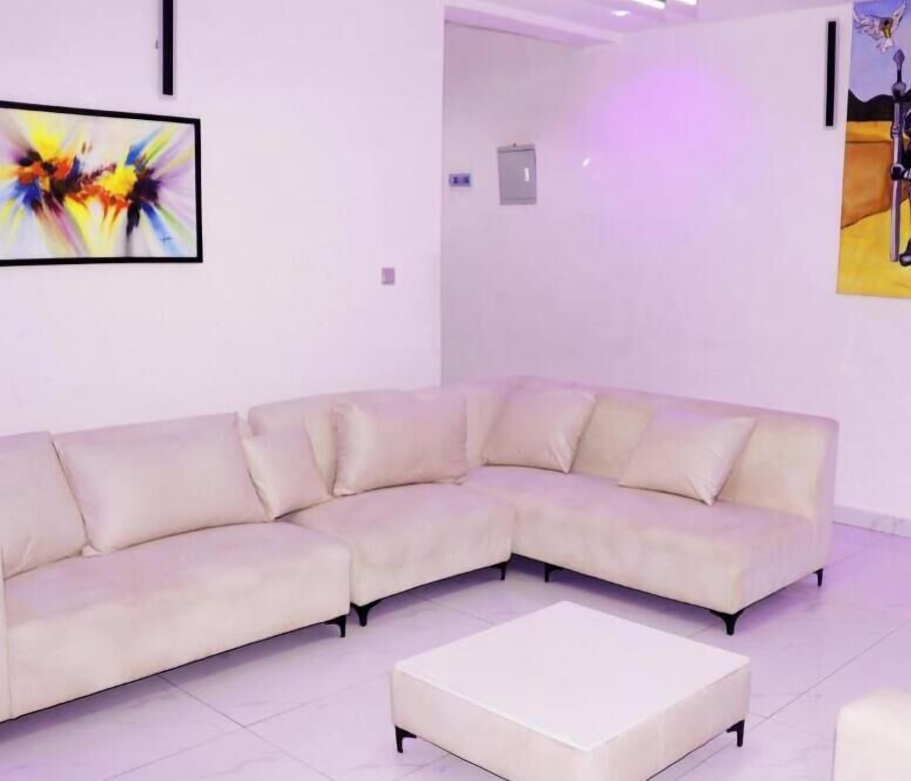 A modern living room with a beige sectional sofa, a white coffee table, and a painting on the wall.