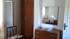 A bedroom with a wooden wardrobe, a bedside table with a mirror, a chair, and a dresser. - Verde Mare Beach Houses (Contrada Taverna)