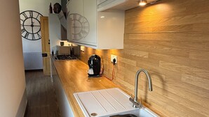 A modern kitchen with a wooden countertop, a stainless steel sink, and a clock on the wall. - SPACIOUS 3 BEDROOM VICTORIAN FLAT IN DUNFERMLINE. VERY NEAR TOWN CENTRE ! (Dunfermline)